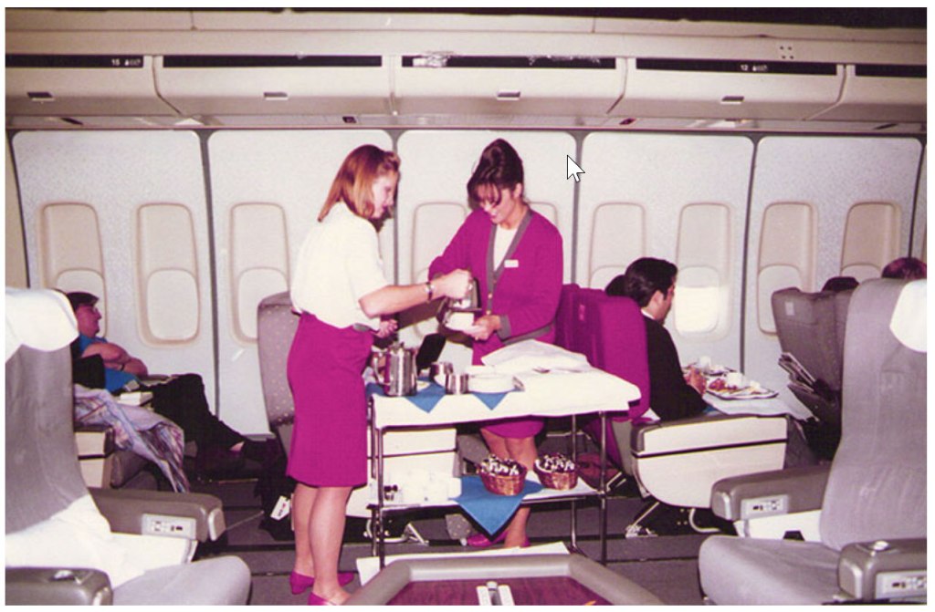 two stewardesses serving on a first class afternoon tea trolley during a flight