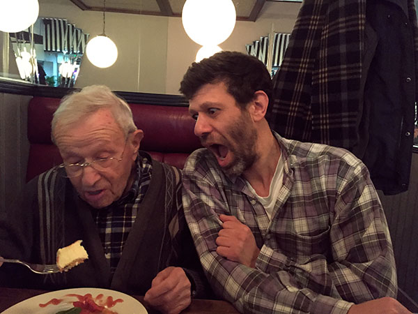 father and son in a restaurant father is eating cheesecake