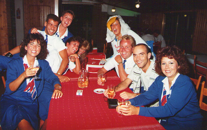 Group of happy laughing Thomson Holidays reps around a table smiling for the camera