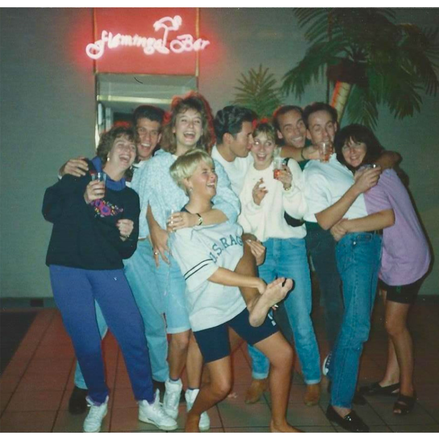 small group of friends holding drinks whilst laughing towards the camera