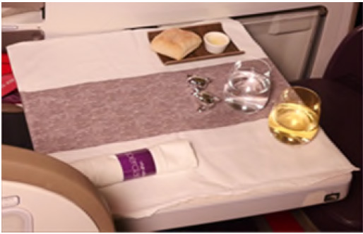 small table laid up with cutlery, salt and pepper bread plate with a roll, wine and water glasses