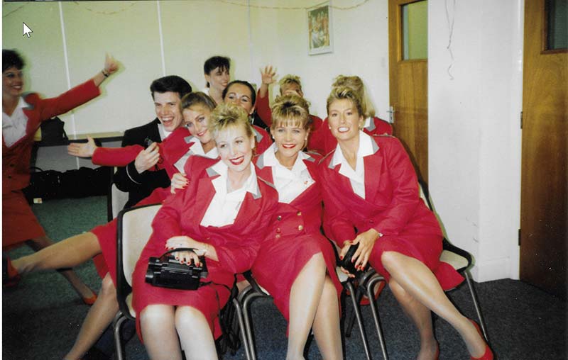 a group of smiling female cabin crew with one male cabin crew member